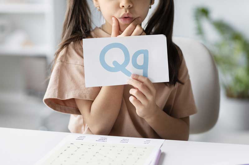 little-girl-holding-paper-with-letter-on-it-in-speech-therapy